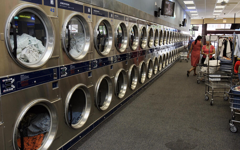 Berwyn, UNITED STATES:  WORLD'S LARGEST LAUNDROMAT RUNS ON SOLAR POWER: A long row of laundry dryers are shown 01 June, 2006 at the self-proclaimed 'World Largest Laundromat' 01 June 2006 in Berwyn, Illinois. The laundry operates 145 washing machines and 125 dryers and is open 24 hours a day. Located on the roof of the laundromat, 24 solar collectors displace an average of 1.4 million British Thermal Units of natural gas per day for washing clothes, saving USD 2,000 per month.  Representing about 60 percent of the energy required for heating water at the facility, conventional gas-fired water heaters provide the remainder. Over the course of a year, the solar system heats 300,000 gallons of water to 120 degrees and, according to Solar Service, is expected to operate for 30 years.  AFP PHOTO/Jeff HAYNES  (Photo credit should read JEFF HAYNES/AFP via Getty Images)
