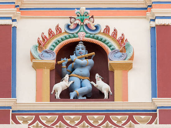 Chettinad, India - October 17, 2013: Chidambara Palace in Kadiapatti. Blue Krishna playing flute and dancing goats statue on front facade. Set in framed niche.