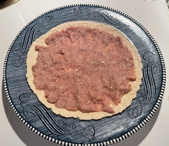 smash burger meat spread out on tortilla