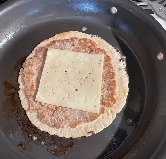 tortilla and meat in skillet with cheese on top