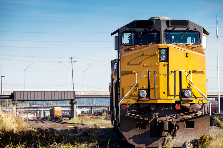 A yellow freight train locomotive sitting idle at an industrial railyard