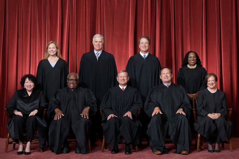 Formal group photograph of the Supreme Court as it was been comprised on June 30, 2022 after Justice Ketanji Brown Jackson joined the Court.  The Justices are posed in front of red velvet drapes and arranged by seniority, with five seated and four standing...Seated from left are Justices Sonia Sotomayor, Clarence Thomas, Chief Justice John G. Roberts, Jr., and Justices Samuel A. Alito and Elena Kagan.  .Standing from left are Justices Amy Coney Barrett, Neil M. Gorsuch, Brett M. Kavanaugh, and Ketanji Brown Jackson...Credit: Fred Schilling, Collection of the Supreme Court of the United States.