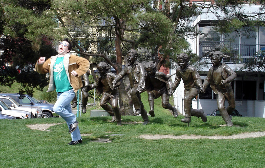 A real man runs in terror in front of a group of statues that appear to be chasing him.