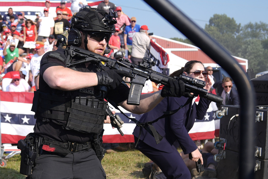 U.S. Secret Service agents surround the stage as other agents cover Republican presidential candidate former President Donald Trump at a campaign rally, Saturday, July 13, 2024, in Butler, Pa. (AP Photo/Evan Vucci)