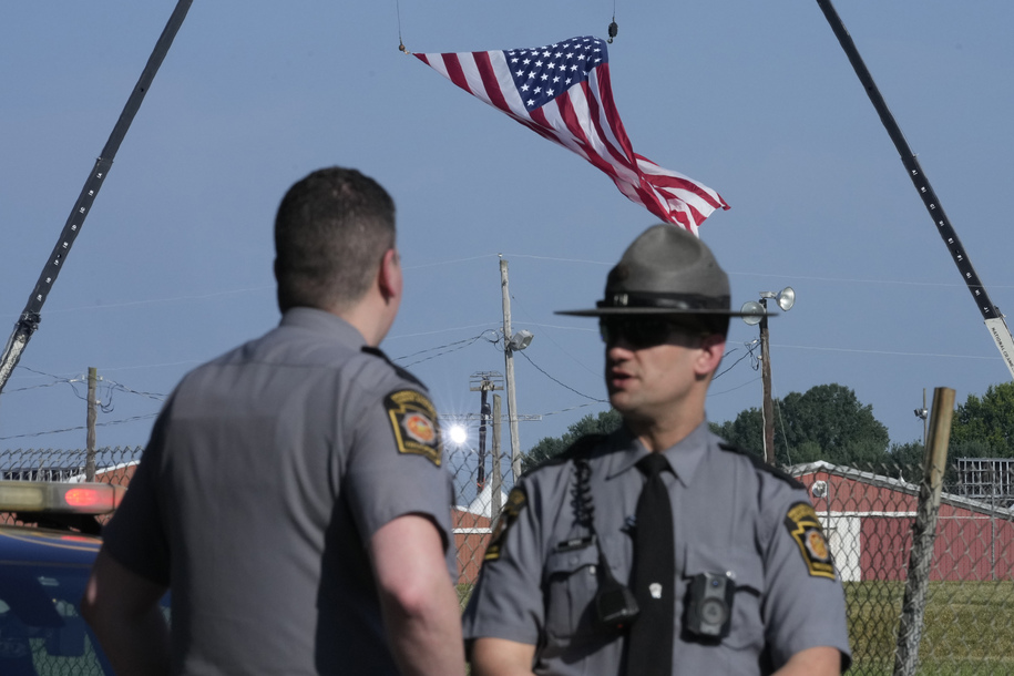 Police officers stand at a road leading to the site of the Trump rally, where access is closed, as investigations into the assassination attempt on former President Donald Trump continue, in Butler, Pa., Sunday, July 14, 2024. (AP Photo/Sue Ogrocki