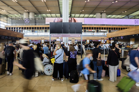 Numerous passengers wait in front of a black display board at the capital's Berlin Brandenburg Airport, in Schönefeld, Germany, Friday July 19, 2024, after a widespread technology outage disrupted flights, banks, media outlets and companies around the world. (Christoph Soeder/dpa via AP)